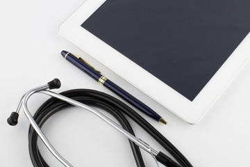 Tablet computer, metal gold-blue pen and stethoscope on a white background