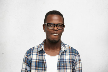 Studio shot of African student having fun making mouths, showing upper teeth like rabbit, looking...