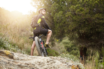 Nature, travel, hiking, cycling and extreme sports concept. Rear shot of young male cyclist in...
