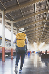 Young woman waiting on the station platform with backpack on train station