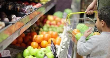 Mother and son buying fruit and vegetables in grocery store - Powered by Adobe