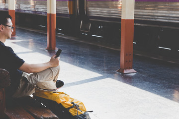 Young man waiting on the station platform with backpack on train station