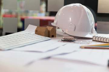 Structural engineer and architect desk with safety helmet, blueprint and model house
