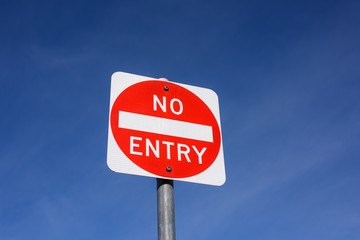 A square red NO ENTRY traffic sign on blue sky background, in Melbourne, Australia.