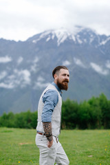 a bearded man dressed in costume on the background on mountains. Summer in Georgia