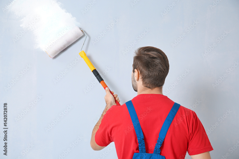 Wall mural young worker painting wall in room