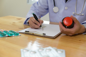 doctor writing RX prescription in medical office clinic with drugs on desk