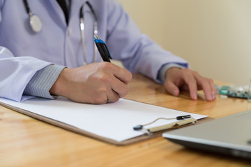 doctor writing RX prescription in medical office clinic with drugs on desk