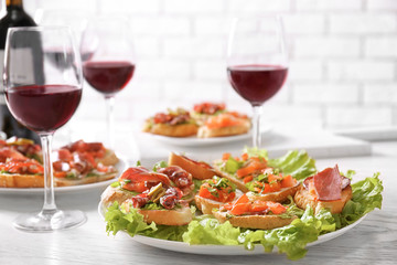 Tasty bruschetta served with wine on light background