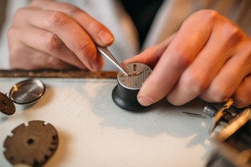 Watchmaker repair broken clockwork with tweezers