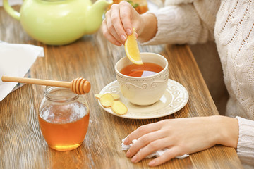 Woman with herbal cup of tea sitting at kitchen table