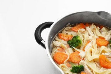Chicken noodle soup in saucepan on white background
