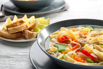 Chicken noodle soup in plate on wooden table, closeup