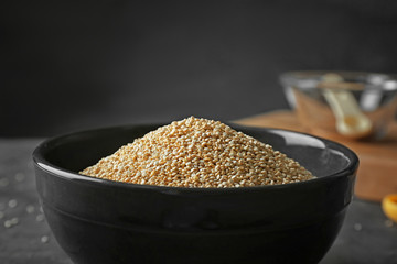 Organic quinoa seeds in bowl on dark background