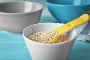 Organic quinoa seeds and scoop in bowl, closeup
