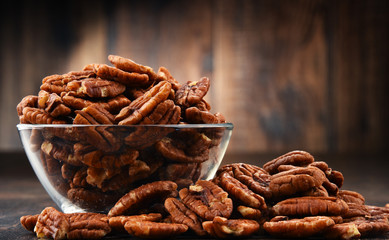 Bowl with pecan nuts on wooden table. - obrazy, fototapety, plakaty