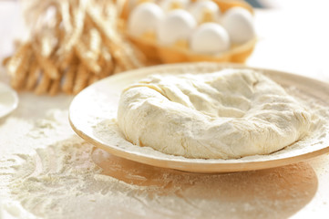 Plate with raw dough on kitchen table