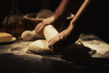 Hands of man rolling dough in kitchen