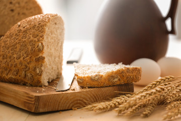 Wooden board with cut bread and knife on kitchen table