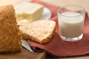 Cut bread, napkin and glass of milk on kitchen table, closeup