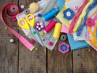 Fototapeta na wymiar Pink, yellow and blue accessories for needlework on wooden background. Knitting, embroidery, sewing. Small business. Income from hobby. Copy space.