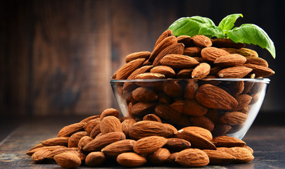 Bowl with shelled almonds on wooden table