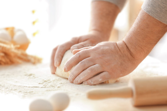Hands of man making dough in kitchen