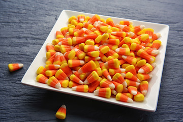 Plate with tasty Halloween candies on dark background