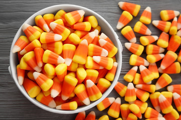 Bucket with tasty Halloween candies on wooden background, closeup