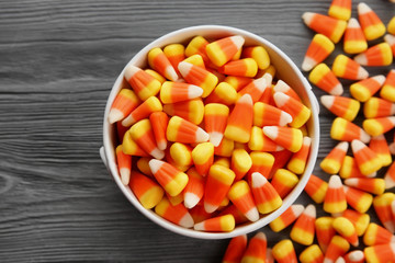 Bucket with tasty Halloween candies on wooden background