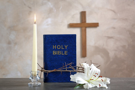 Holy Bible, crown of thorns, lily, candle and cross on beige background