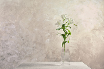 Beautiful white lilies in vase on light background