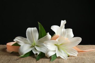 Beautiful lilies and ribbon on black background