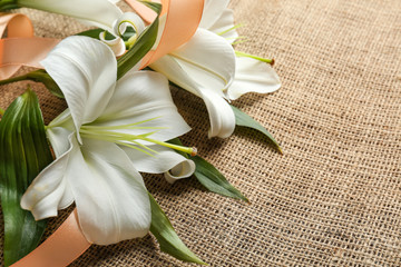 Beautiful lilies and ribbon on fabric background © Africa Studio