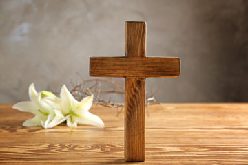 Wooden cross and lily on table
