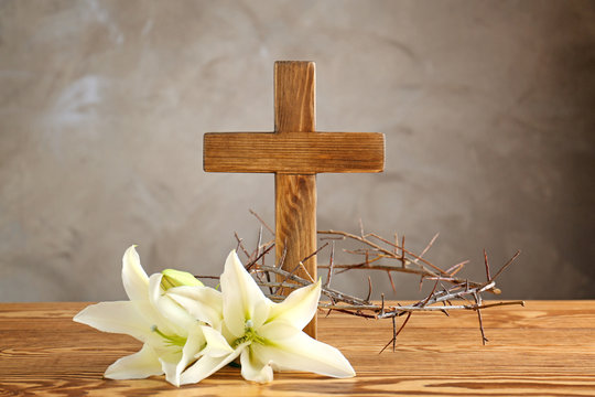 Crown of thorns, wooden cross and white lily on table