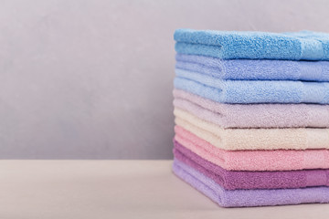 Fototapeta na wymiar Stack of colorful bath towels on light background.