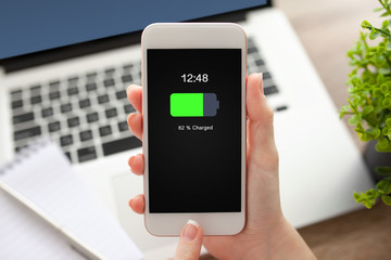 female hand holding white phone with charged battery on screen