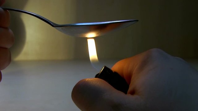 A Man's Hand Lights A Lighter Under A Spoon With Drugs. Addict Prepares Drugs In Home Conditions For Make An Injection