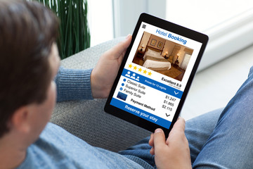 man in jeans holding tablet computer with app hotel booking