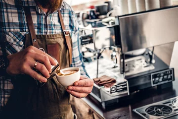 Foto auf Alu-Dibond A man preparing cappuccino in a coffee machine. © Fxquadro