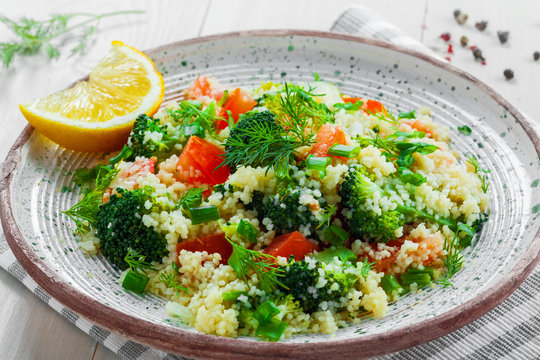 Delicious healthy meal made of couscous, broccoli and other vegetables on a rustic wooden table. Traditional eastern food. Close-up shot.