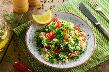 Traditional eastern couscous with broccoli, tomato, pepper, onion and dill on a plate for healthy...