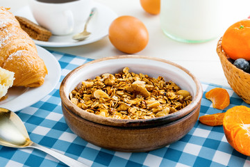 Healthy food for breakfast on a white wooden table. Oatmeal granola with nuts, coffee, croissants, eggs, milk and fruits for delicious healthy meal. Close-up.