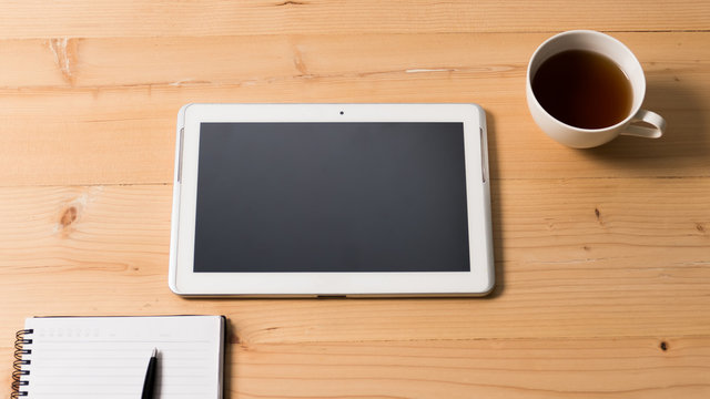 Taplet with notebook on wooden table, Bussiness concept.