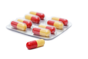 Red and yellow pill and pack of pills on blurred background