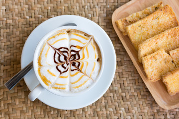 Cappuccino cup with crispy butter toast on weaving a mat