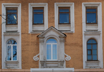 Old tower against the background of the spring sky. Yellow tower, a fragment of the facade.