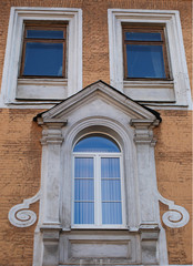 Old tower against the background of the spring sky. Yellow tower, a fragment of the facade.