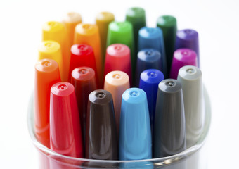 Colored markers in a cup on a white background.